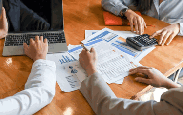Image of table with reports and laptop in a meeting with clients