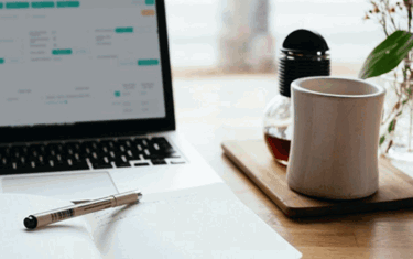 Image of coffee cup and doing taxes on laptop