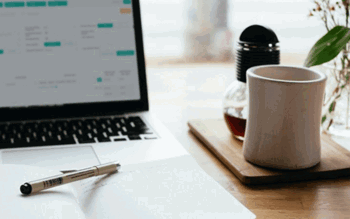 Image of coffee cup and doing taxes on laptop